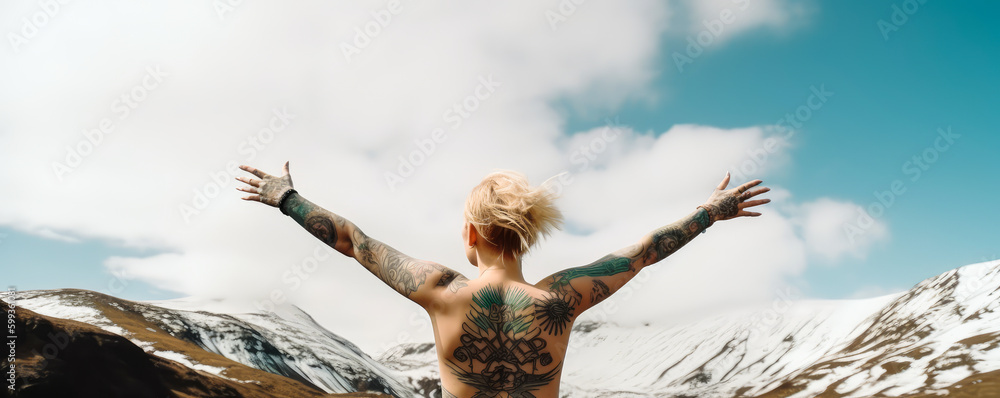 A blonde woman, tattooed and naked from behind, with her arms raised celebrating her