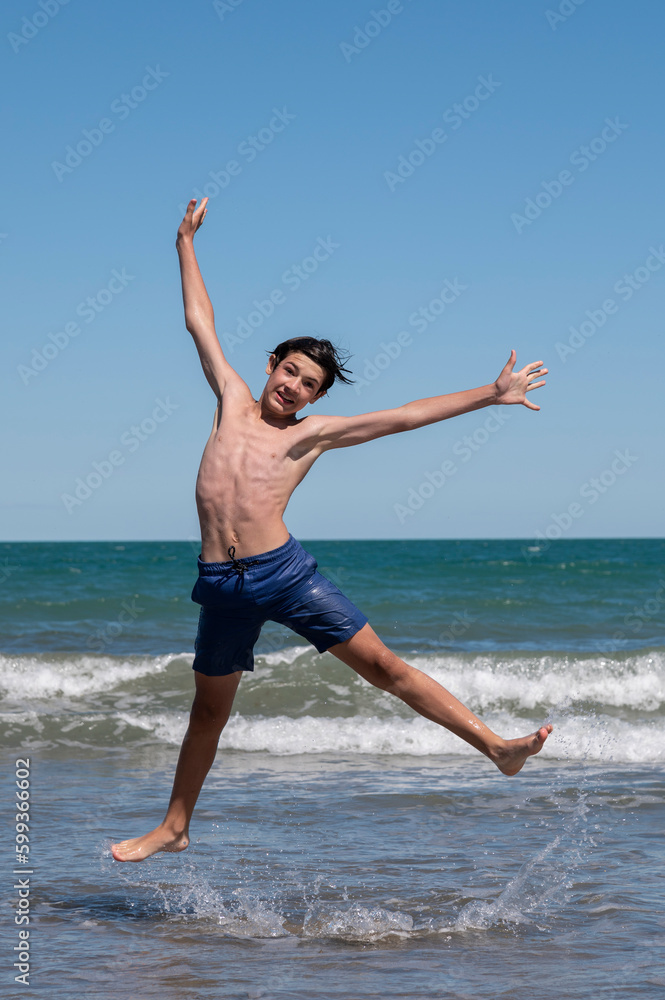 Happy boy performs pirouettes and big jumps on the seashore during his summer vacation on the Atlantic Coast, Las Grutas, Rio Negro, Argentina. Happy boy performs pirouettes and big jumps on the seashore during his summer vacation on the Atlantic Coast, Las Grutas, Rio Negro, Argentina.