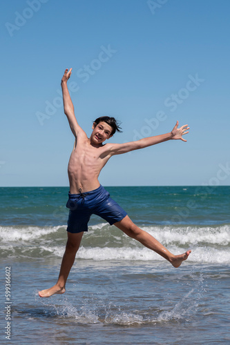 Happy boy performs pirouettes and big jumps on the seashore during his summer vacation on the Atlantic Coast, Las Grutas, Rio Negro, Argentina.