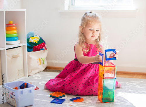 Little child playing with magnet tiles. Toddler caucasian girl playing.	 photo