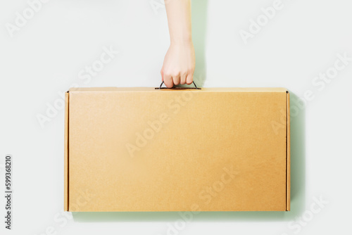 Eco friendly shopping and delivery service concept. Sustainable lifestyle with cardboard box in delivery man hand on light blue background. Plastic free and eco packaging. Mockup, copy space © KRISTINA KUPTSEVICH