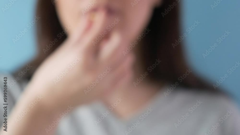 Woman taking gastritis, stomach ulcer, heartburn medicine capsule or pill on blue background with glass of water Woman taking gastritis, stomach ulcer, heartburn medicine capsule or pill on blue background with glass of water