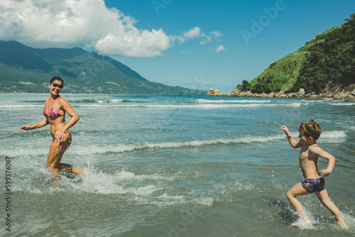 Mãe e filho brincando no mar da praia no verão