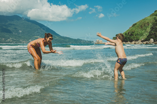 Mãe e filho brincando no mar da praia no verão
