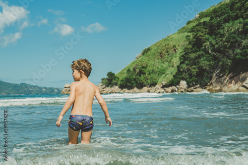 Foto Menino brincando no mar da praia