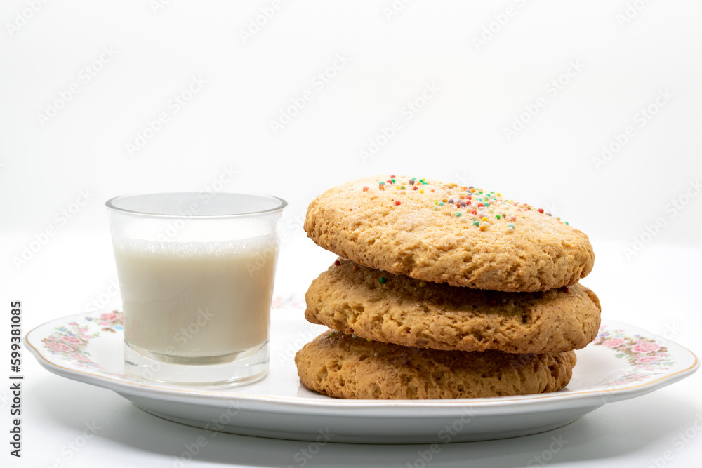 Biscuits next to a cup of milk on a long plate isolated white background selective focus Biscuits next to a cup of milk on a long plate isolated white background selective focus