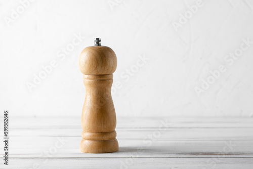 Φωτογραφία Wooden pepper shaker grinder on a white wooden background.
