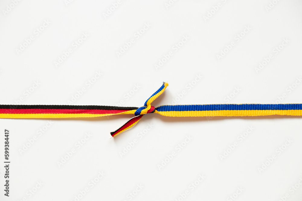 Two ribbons of the flags of Ukraine and Germany are tied in a knot on a white background, friendship and union Two ribbons of the flags of Ukraine and Germany are tied in a knot on a white background, friendship and union