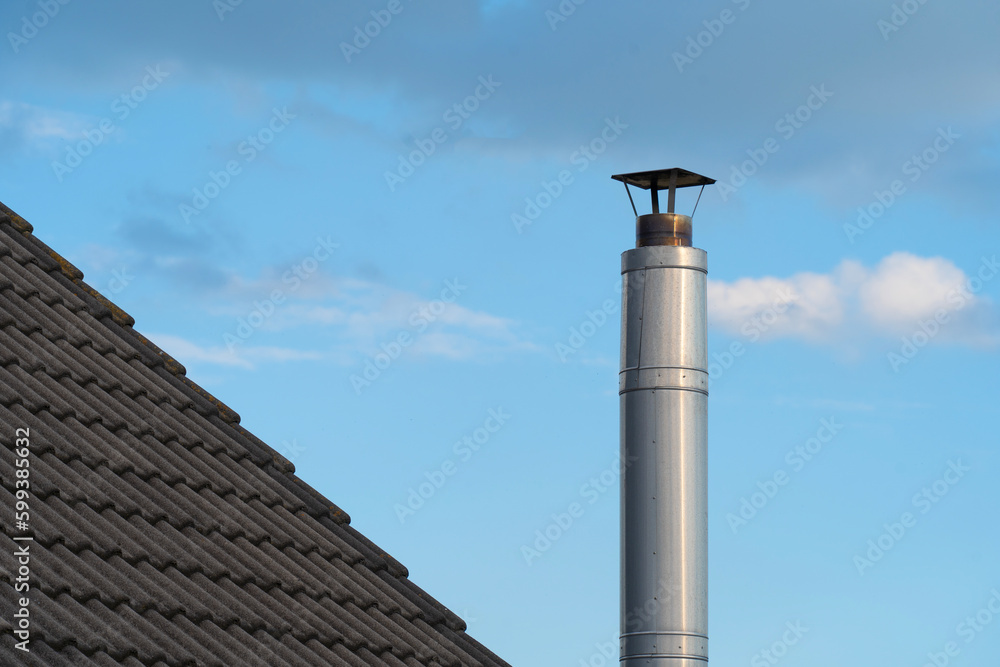 Modern metal chimney on a house with tiled roof Modern metal chimney on a house with tiled roof