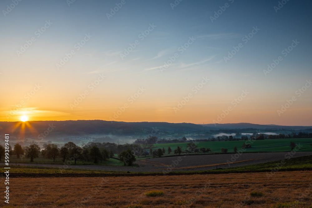 Colourful sunrise on a summer morning with a little fog on the ground and spectacular views over the Dutch hillside near the village of Kuttingen