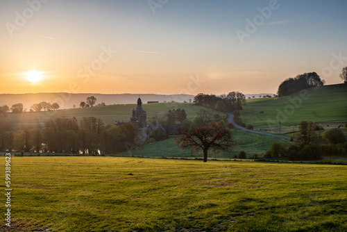 Colourful sunrise on a summer morning with a little fog on the ground and spectacular views over the Dutch hillside and a picturesque castle dating back to the 14th century