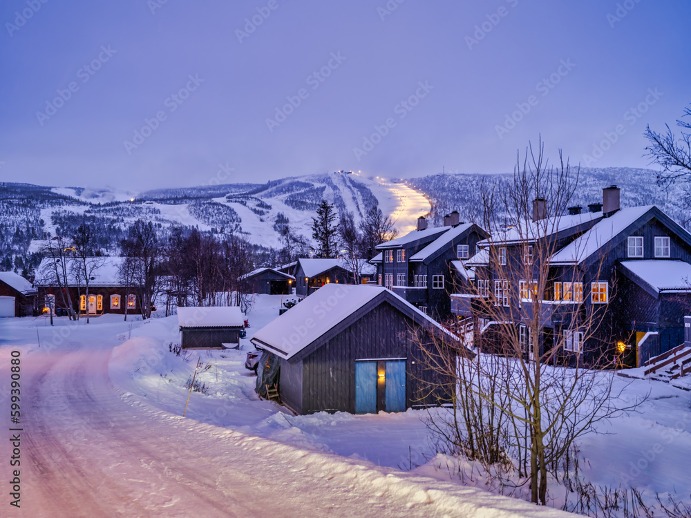 Wooden Norwegen houses and Ski Run in the background litp up after sunset in Geilo, Norway