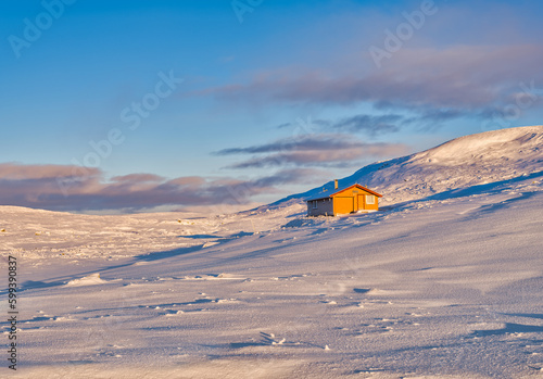 An orange wooden house in a frozen winter wonderland during sunrise in Eidfjord, Norway