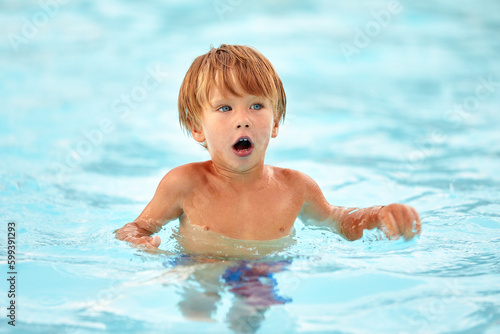 Little boy in blue swimming trunks learns to swim in the pool, joy for children in the water park, children's swimming