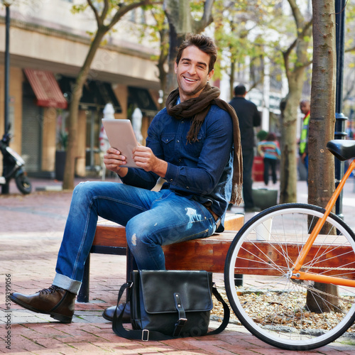 Just taking a breather. a man using his tablet while taking a break in the city with his bicycle beside him.
