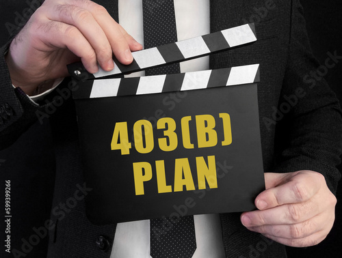 A businessman holds up a ?lapperboard with text 403b plan photo