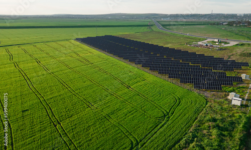 Stunning aerial view of a solar energy park with a backdrop of rolling hills and natural scenery, featuring solar panels in neat rows, representing the perfect blend of technology and nature. © Vadim