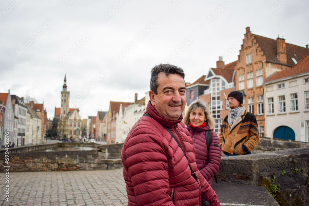 Fototapeta premium Caucasian family on bridge in Bruges town, Belgium. Adult couple, turist walking on the canal, posing for the picture.