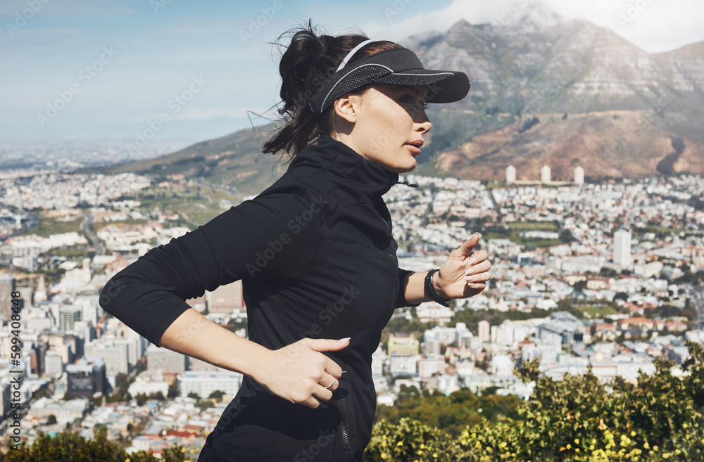 Naklejka premium Going places one step at a time. a determined young woman going for a jog on her own with a view of the city in the background.