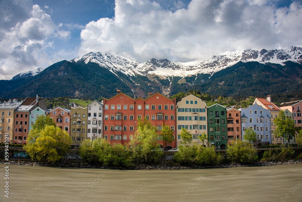 City of Innsbruck in Tirol, Austria with its colorful buildings, the Inn river and a snowy mountain range in the background 