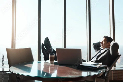 Obraz Hard work truly does pay off. a young businessman relaxing with his feet up on a table in an office.