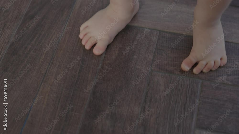 tiny barefoot legs baby child doing first steps, learning balancing stand still near window. Daytime sun beams light little toddler toes and heels. baby learn to walk stand on tip toes wooden floor. tiny barefoot legs baby child doing first steps, learning balancing stand still near window. Daytime sun beams light little toddler toes and heels. baby learn to walk stand on tip toes wooden floor.