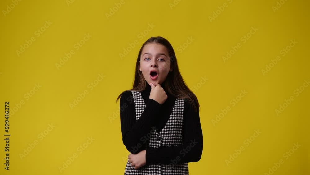 4k video of one young girl planning something and points upwards on yellow background. 4k video of one young girl planning something and points upwards on yellow background.