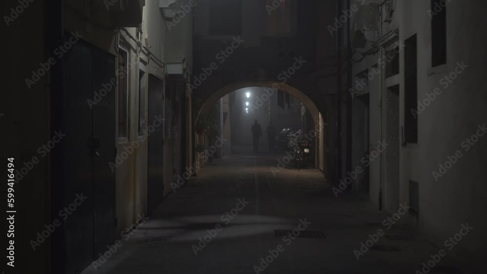 People walk along narrow street between old buildings People walk along narrow street between old buildings