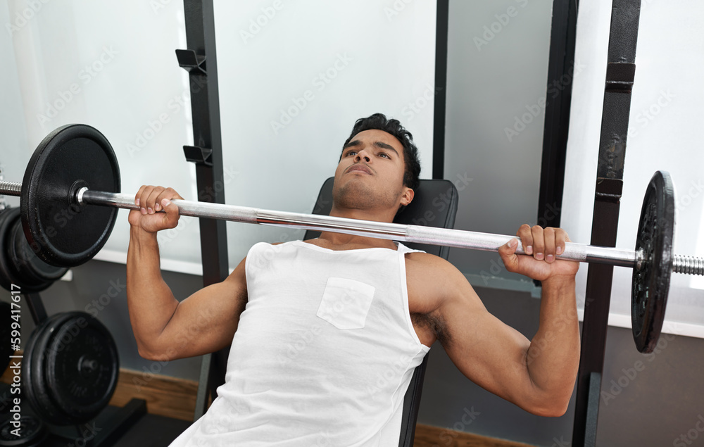 Bulking up his body. A young ethnic man lifting a heavy barbell. Bulking up his body. A young ethnic man lifting a heavy barbell.