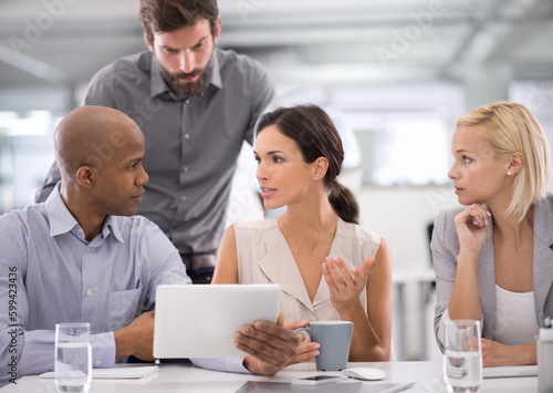 Finalising figures. a group of businesspeople discussing the contents of a tablet during a meeting.
