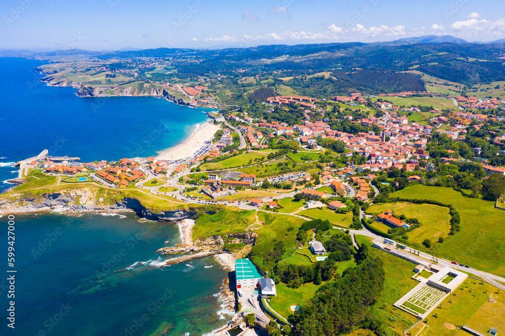 Aerial panoramic view of summer landscape overlooking small Spanish town of Comillas on coast of Cantabrian Sea..