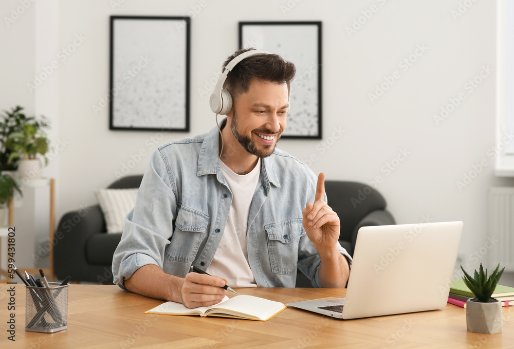 Man in headphones studying on laptop at home. Online translation course Man in headphones studying on laptop at home. Online translation course
