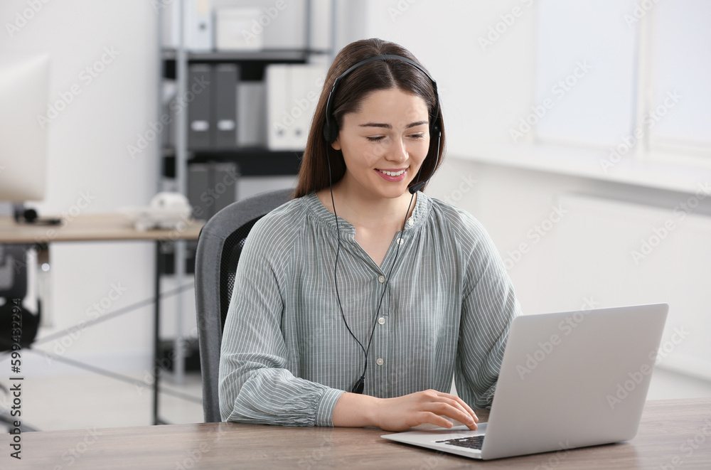 Hotline operator with headset working on laptop in office Hotline operator with headset working on laptop in office