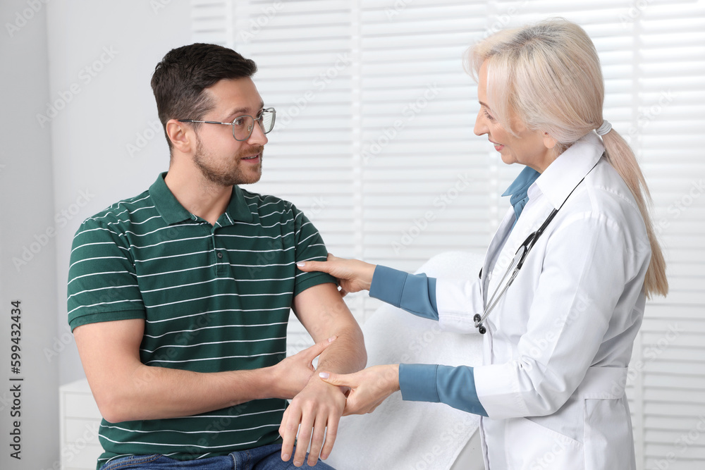 Doctor checking patient's pulse during consultation in clinic Doctor checking patient's pulse during consultation in clinic