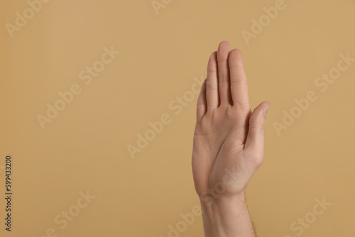 Man giving high five on beige background, closeup of hand. Space for text