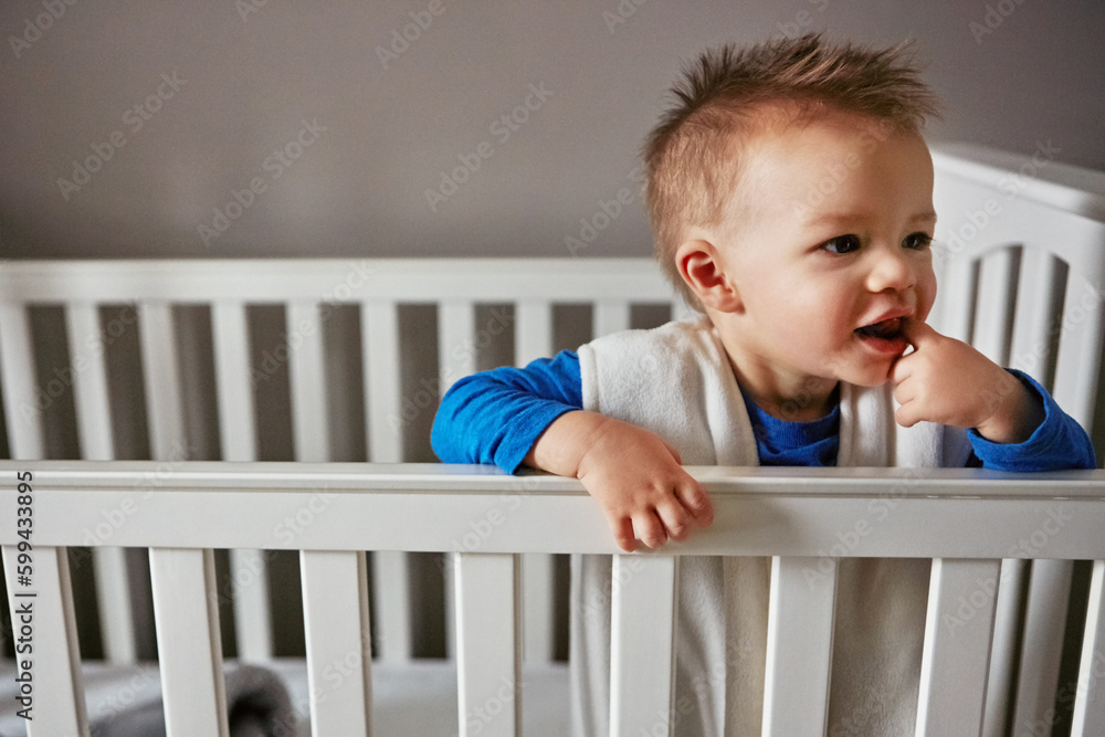 its their world, we just live in it. a cute little baby boy standing in his cot. its their world, we just live in it. a cute little baby boy standing in his cot.