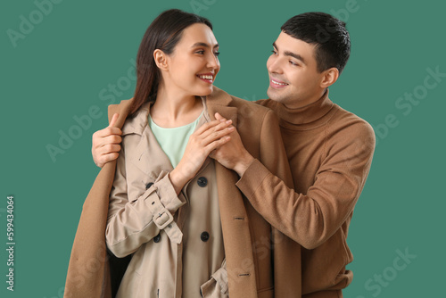 Young man putting coat onto...