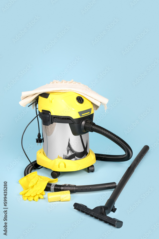 Vacuum cleaner with carpet and rubber gloves on blue background Vacuum cleaner with carpet and rubber gloves on blue background