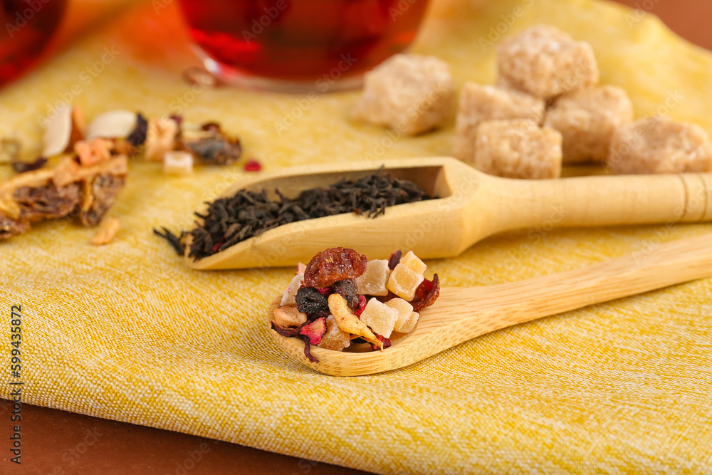 Wooden spoon and scoop with dried fruit tea on napkin, closeup