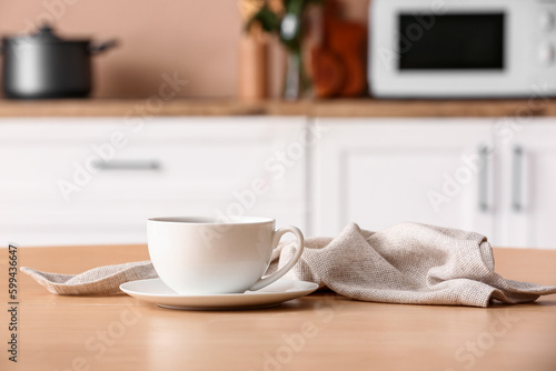 Fototapeta Naklejka Na Ścianę i Meble -  Saucer with cup and napkin on wooden table in kitchen