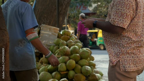 Tender coconut water seller and buyer exchanging money, cash, and currency in the marketplace during a transaction, India photo