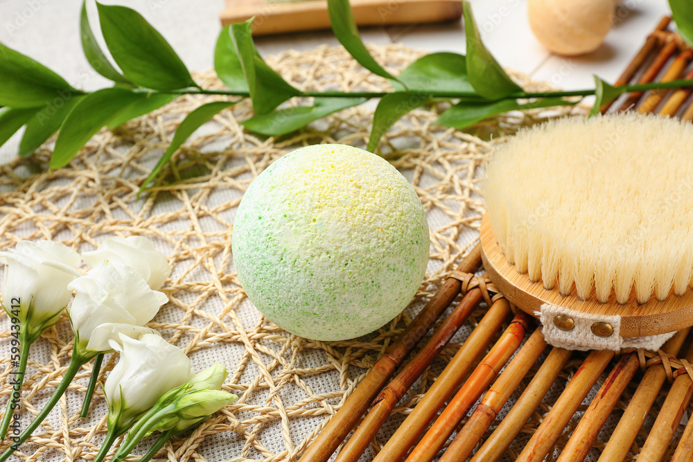 Bath bomb with massage brush, roses and plant branch on mat, closeup Bath bomb with massage brush, roses and plant branch on mat, closeup