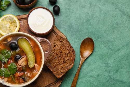 Pot of tasty Hodgepodge soup with sour cream and bread on grunge background photo