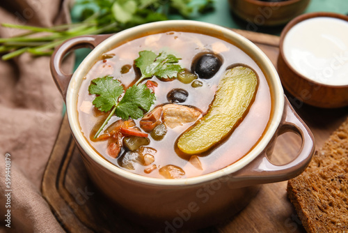 Pot of tasty Hodgepodge soup on table, closeup photo