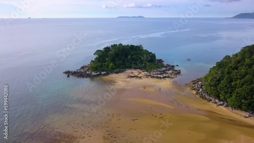 Zoom out aerial shot of a small rock island with trees at Kampung Paya in Tioman Island, Malaysia photo