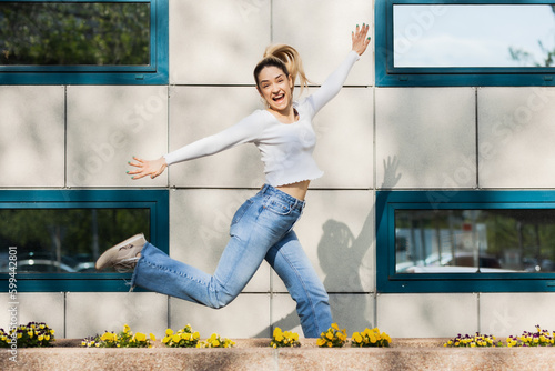 Beautiful girl jumping infront of modern building facade. photo