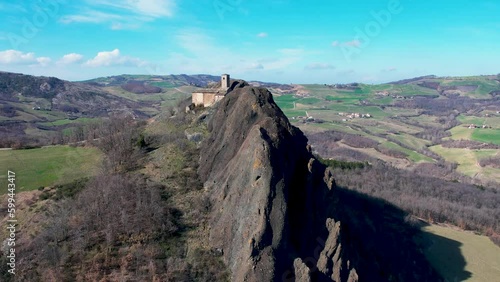 Aerial footage of Pietra Perduca, volcanic rock, church set at top stone immersed in countryside landscape, cultivated land in Val Trebbia Bobbio, Emilia Romagna, Italy photo