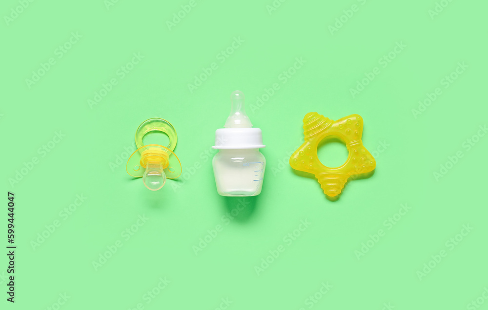 Bottle of milk for baby and accessories on pale green background Bottle of milk for baby and accessories on pale green background