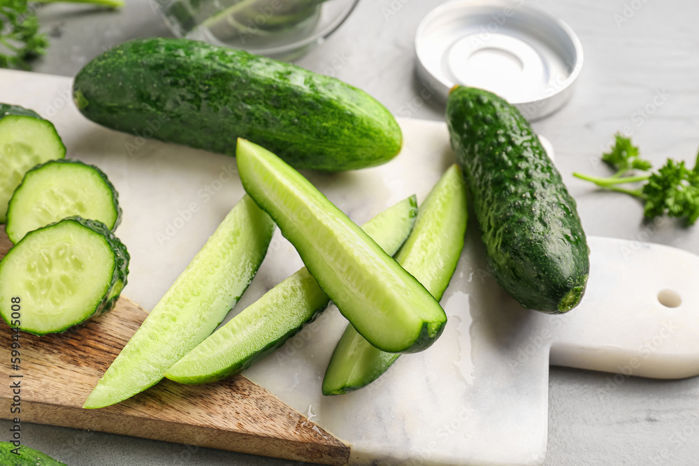 Board with fresh cut cucumbers on grey background Board with fresh cut cucumbers on grey background