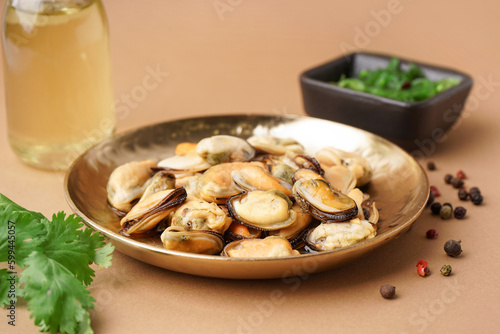 Plate with pickled mussels and bowl of seaweed salad on brown background